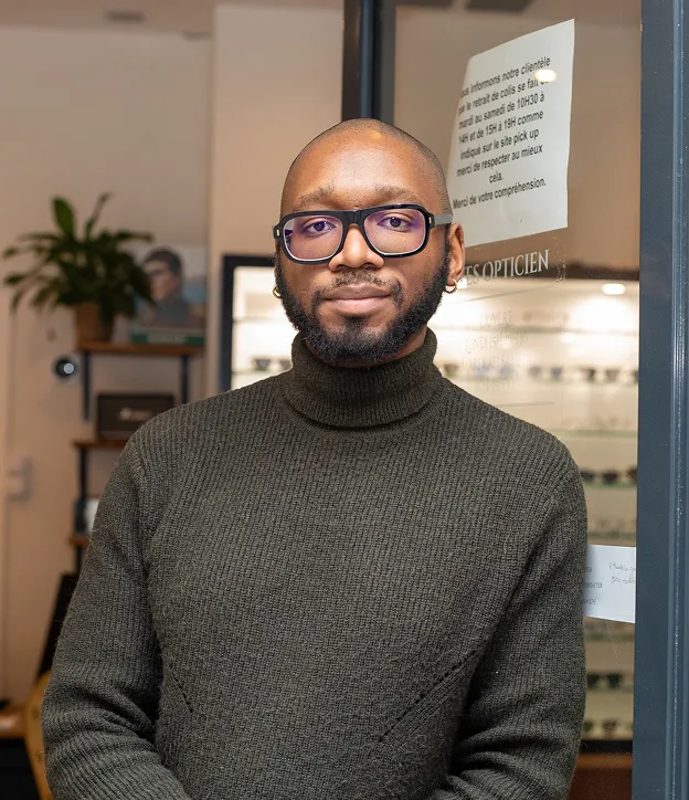 Façade de la boutique Yves Opticien, lunettes exposées, branches d'arbres floues au premier plan à Montrouge dans les Hauts-de-Seine 92