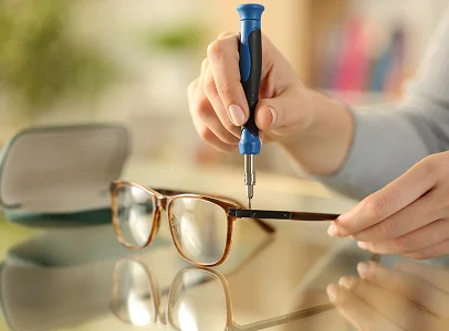 Mains réparant des lunettes cassées avec un petit tournevis sur une table à Montrouge dans les Hauts-de-Seine 92