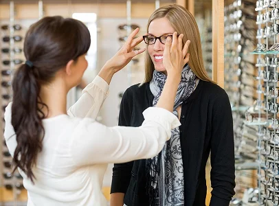 Opticien aidant une femme à essayer des lunettes dans un magasin à Montrouge dans les Hauts-de-Seine 92