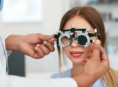 Opticien ajustant un phoroptère sur une jeune femme souriante lors d'un examen de la vue à Montrouge dans les Hauts-de-Seine 92