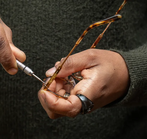 Mains ajustant des lunettes œil-de-chat écaille de tortue avec un petit tournevis à Montrouge dans les Hauts-de-Seine 92