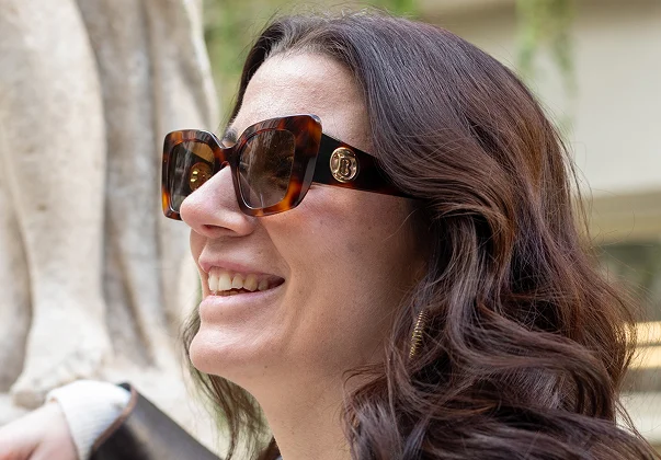 Femme souriante aux cheveux bruns et lunettes de soleil écaille de tortue avec le logo Burberry à Montrouge dans les Hauts-de-Seine 92