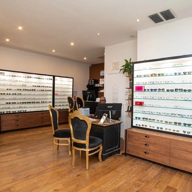 Intérieur d'un magasin d'optique avec des lunettes exposées et un employé à son bureau à Montrouge dans les Hauts-de-Seine 92