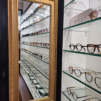 Présentoir de lunettes dans un magasin d'optique, avec des montures et des lunettes de soleil.