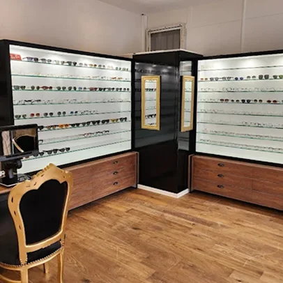 Opticien moderne avec des lunettes exposées sur des étagères illuminées et un sol en bois.